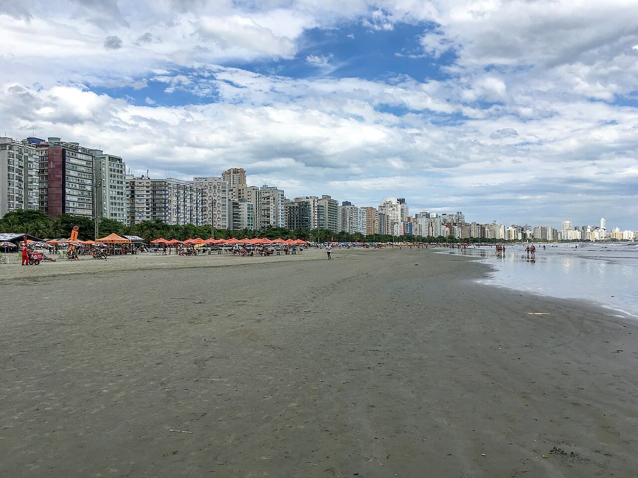 Faixa de areia larga da praia do Boqueirão em Santos, com a linha de prédios do bairro ao fundo